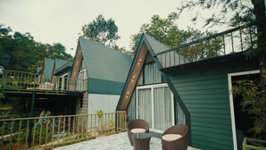 Una propiedad residencial con balcón, dos sillas de mimbre y piso con diseño.