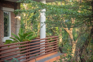 A wooden staircase leading to a porch with a brick wall and a window. - Laoxao River Homestay
A charming riverside hotel where natural beauty (Đà Nẵng)