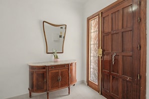 A wooden door with a glass panel, a marble-top cabinet with drawers, and a wall-mounted mirror. - Apartment 'El Olivo 2' with 2 Private Terraces, Wi-Fi, and Air Conditioning (Málaga)