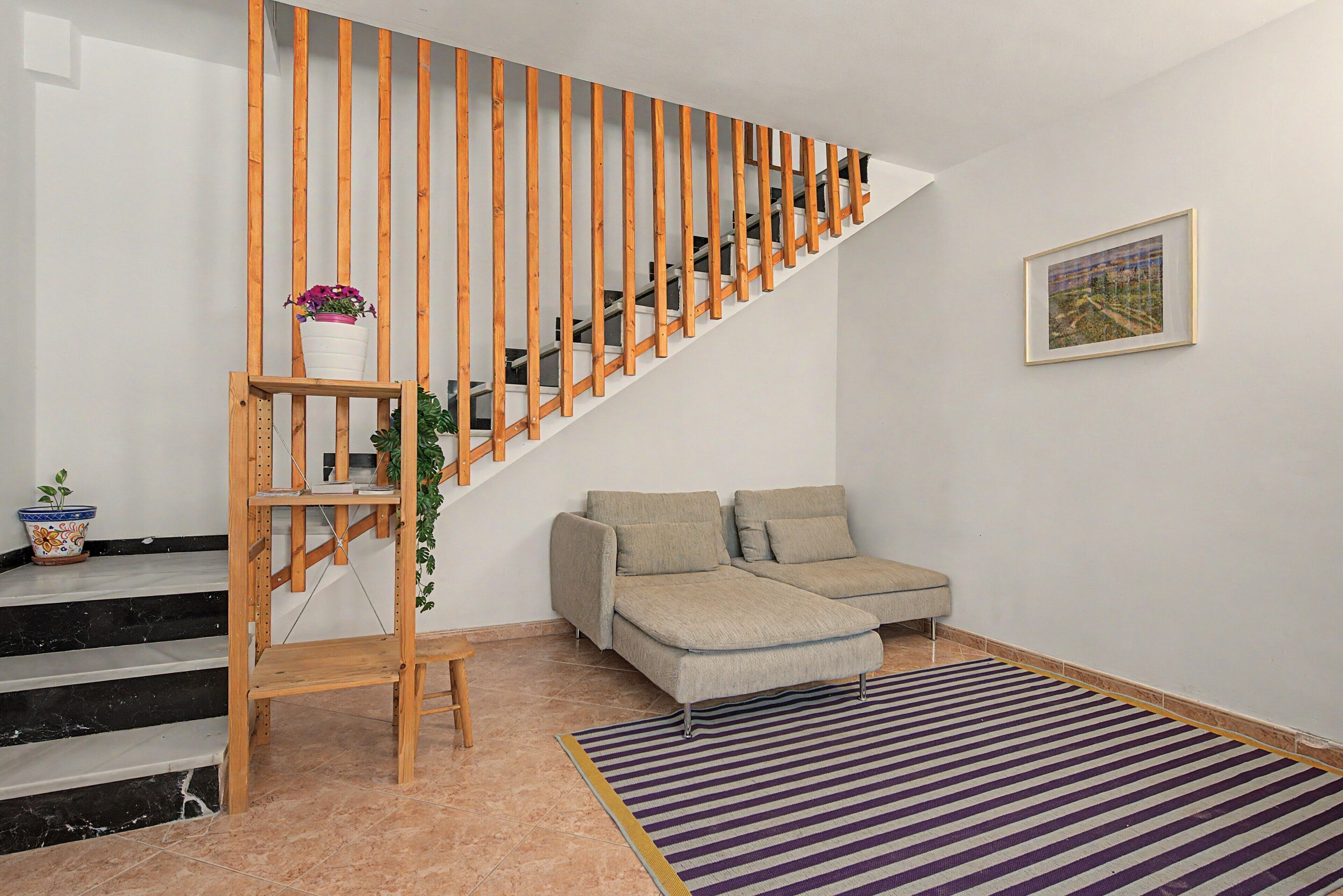 Un interior moderno con una escalera de madera, un sofá y una alfombra a rayas.