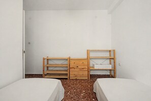 A room with two beds, a wooden dresser, and a shelf unit. - Apartment 'El Olivo 2' with 2 Private Terraces, Wi-Fi, and Air Conditioning (Málaga)