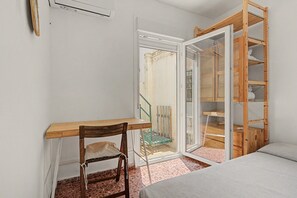 A small, compact room with a wooden desk, a chair, a bed, and a built-in shelving unit. - Apartment 'El Olivo 2' with 2 Private Terraces, Wi-Fi, and Air Conditioning (Málaga)