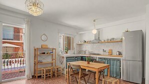 Moderni keittiö, jossa on ruokailutila, jääkaappi ja näkymä ulos.