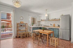 A modern kitchen with a dining area, a refrigerator, and a view of the outside. - Apartment 'El Olivo 2' with 2 Private Terraces, Wi-Fi, and Air Conditioning (Málaga)