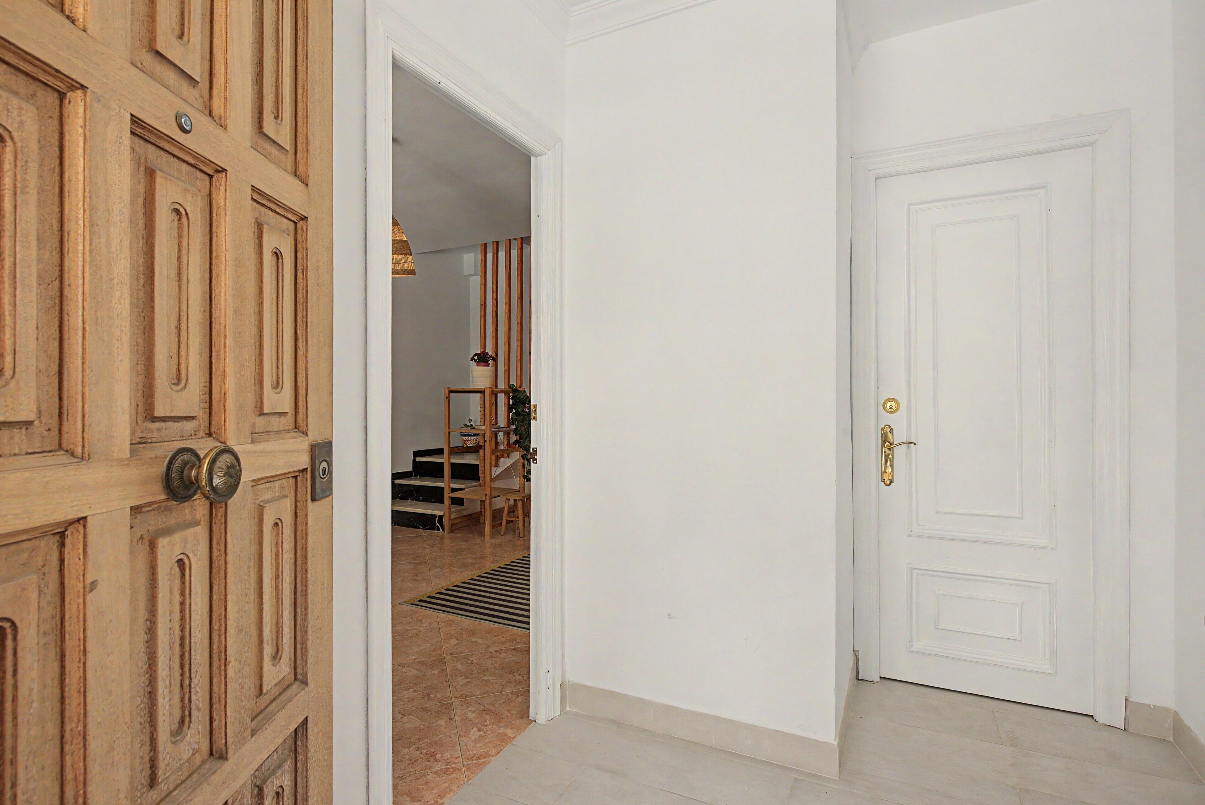 Un pasillo con una puerta de madera a la izquierda y una puerta blanca a la derecha.