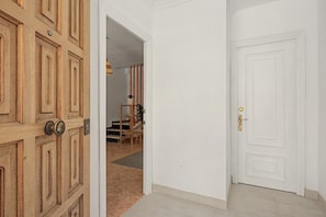 A hallway with a wooden door on the left and a white door on the right. - Apartment 'El Olivo 2' with 2 Private Terraces, Wi-Fi, and Air Conditioning (Málaga)