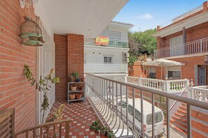 Ein Balkon mit Fliesenboden, Blumentöpfen und einem weißen Lieferwagen darunter.
