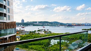 A high-rise building with a view of a river, boats, and a distant cityscape. - The Ruby Ha Long by LN Maison (cao xanh)