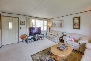 Una sala de estar con televisor, sofá, mesa de centro y cojines decorativos.