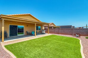 A house with a covered patio, a lawn, and a view of the surrounding area. - Walk to Tucson Trails! Private Yard w/ Views (Tucson)