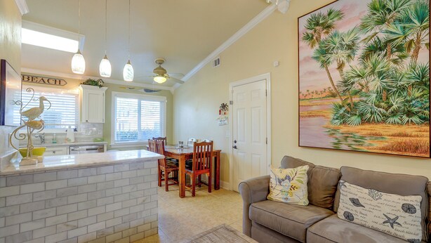 A kitchen with a white countertop, wooden chairs, and a dining table. - Flip-Flop to Beach & Flagler Ave! Breezy Getaway (New Smyrna Beach)