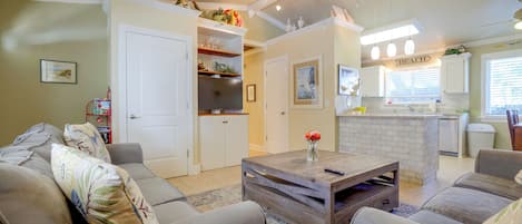 A living room with a sofa, a coffee table, and a kitchen area with a countertop and cabinets.