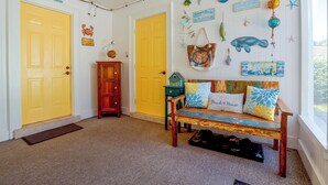 A room with two yellow doors, a wooden bench with beach-themed cushions, and various nautical decorations on the walls. - Flip-Flop to Beach & Flagler Ave! Breezy Getaway (New Smyrna Beach)