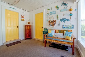 A room with two yellow doors, a wooden bench with beach-themed cushions, and various nautical decorations on the walls. - Flip-Flop to Beach & Flagler Ave! Breezy Getaway (New Smyrna Beach)