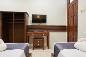 Habitación de hotel con dos camas, un escritorio de madera, un televisor y un armario.