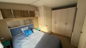 Un dormitorio con cama, armario y mesita de noche.