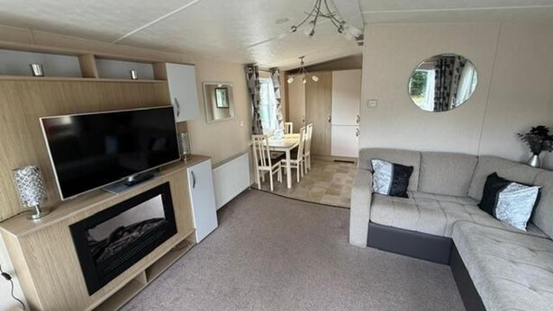 Un espacio habitable compacto con televisión de pantalla plana, un sofá, comedor y un espejo.