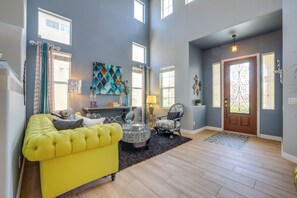 A spacious living room with a high ceiling, a yellow sofa, a patterned armchair, and a decorative fireplace. - Spacious Vegas Retreat < 10 Mi to the Strip! (Las Vegas)