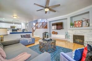 A modern living room with a fireplace, a staircase, and a kitchen in the background. - Spacious Vegas Retreat < 10 Mi to the Strip! (Las Vegas)