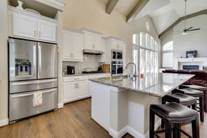 A modern kitchen with white cabinetry, stainless steel appliances, and a large island with bar stools. - Spacious Rowlett Home | Ideal for Extended Stays (Rowlett)