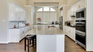 A spacious kitchen with white cabinetry, granite countertops, and stainless steel appliances. - Spacious Rowlett Home | Ideal for Extended Stays (Rowlett)