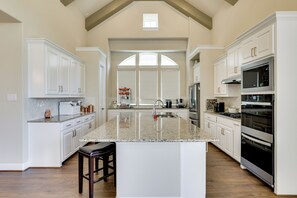 A spacious kitchen with white cabinetry, granite countertops, and stainless steel appliances. - Spacious Rowlett Home | Ideal for Extended Stays (Rowlett)