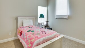 A bedroom with a bed, a chair, a window, and a lamp. - Spacious Rowlett Home | Ideal for Extended Stays (Rowlett)