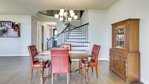 A dining area with a wooden table and chairs, a staircase, and a wooden cabinet. - Spacious Rowlett Home | Ideal for Extended Stays (Rowlett)