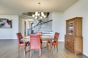 A dining area with a wooden table and chairs, a staircase, and a wooden cabinet. - Spacious Rowlett Home | Ideal for Extended Stays (Rowlett)