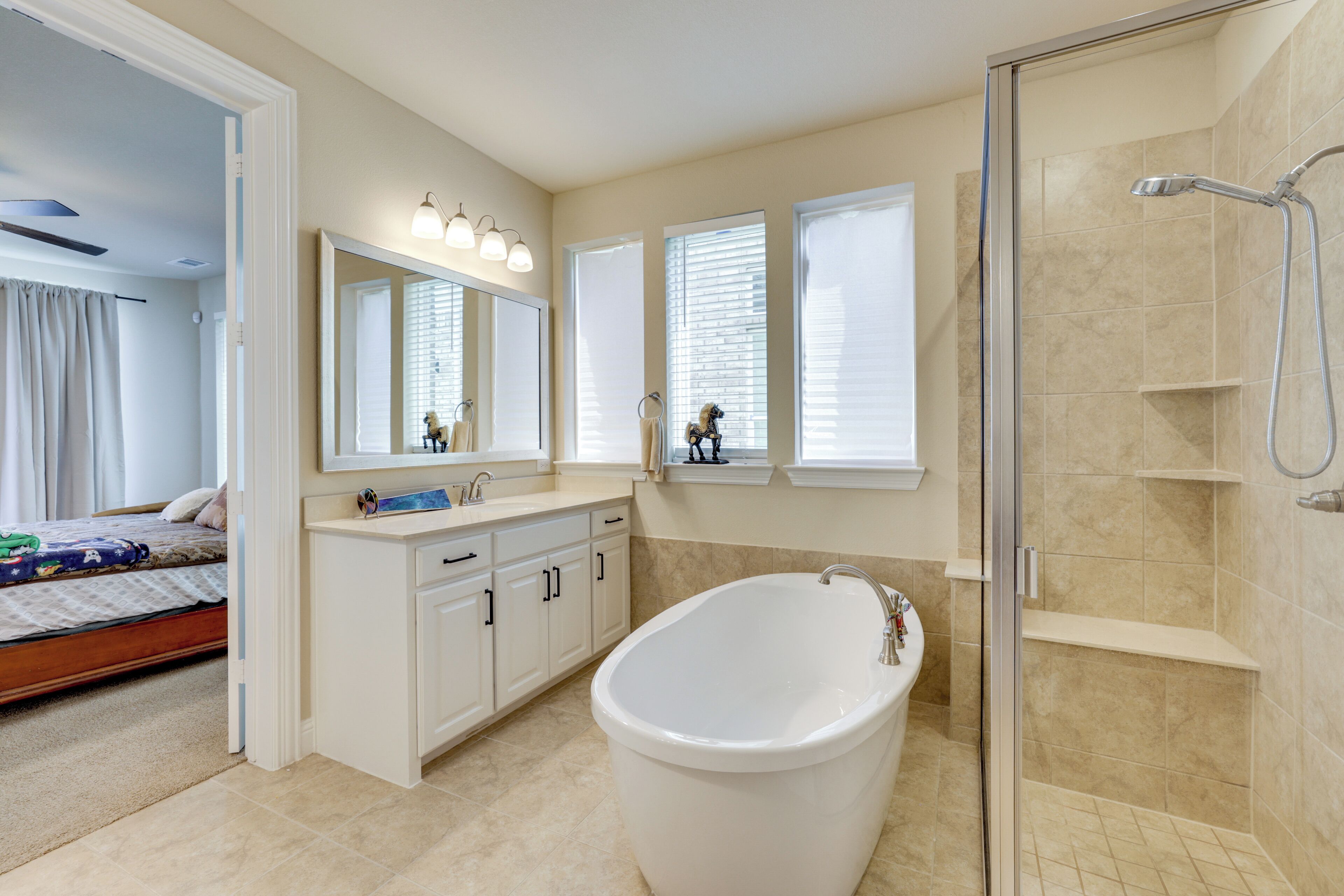 A bathroom with a bathtub, a shower, and a vanity with a mirror.