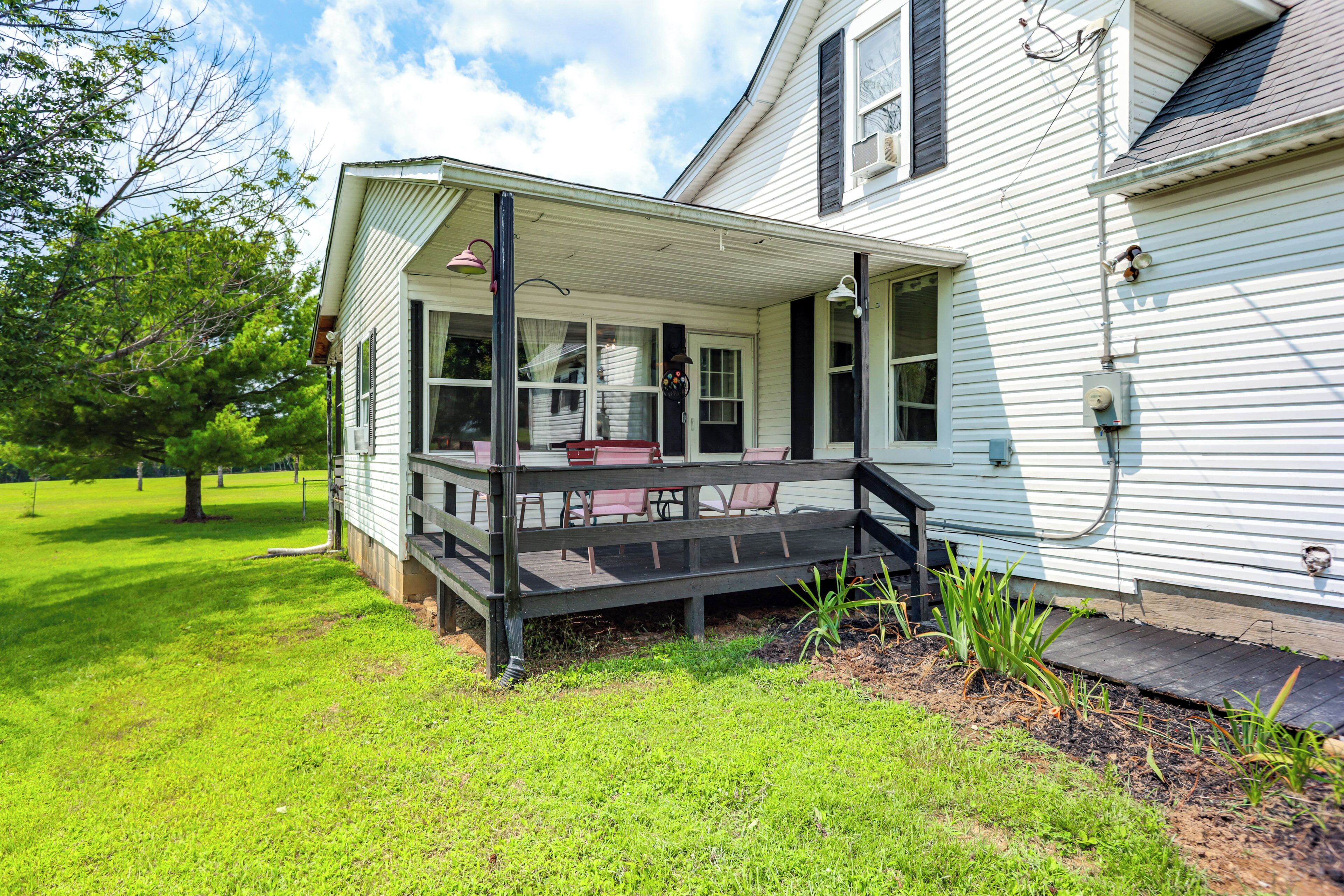A house with a porch, a small garden, and a tree.