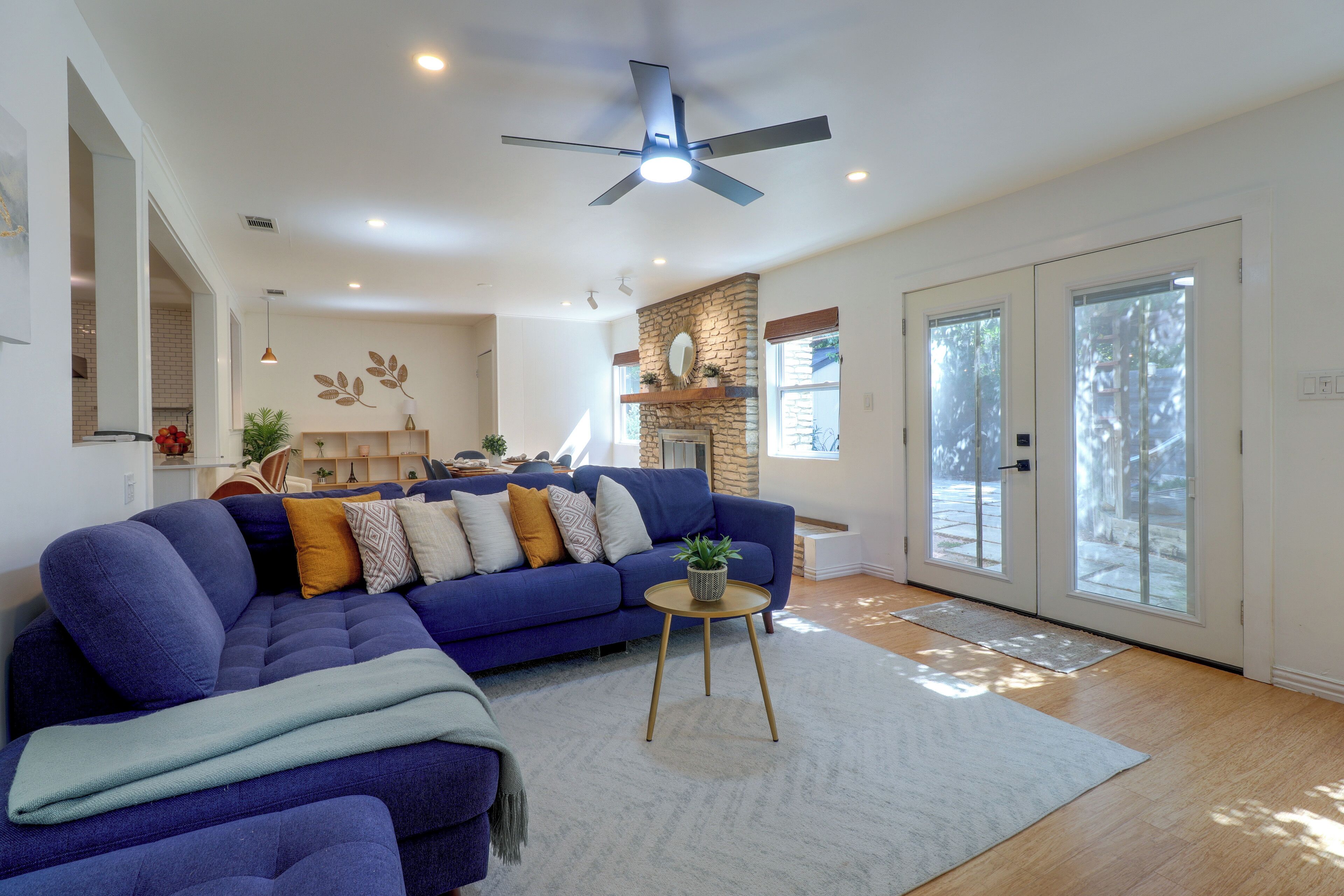 A modern living room with a sectional sofa, a ceiling fan, and a stone accent wall.