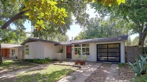 Une maison à deux étages avec un garage, un porche à l’avant doté de chaises et une pelouse bien entretenue.