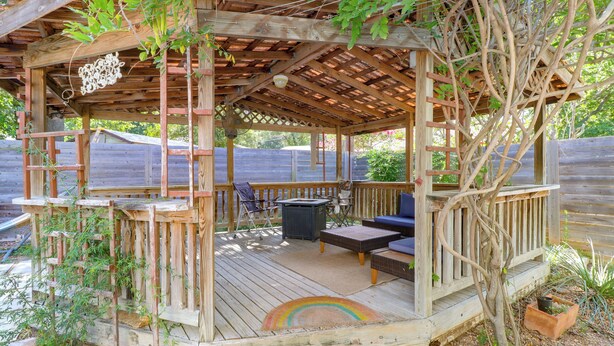 Une terrasse en bois dotée d’un espace salon couvert, comprenant une table et des chaises.