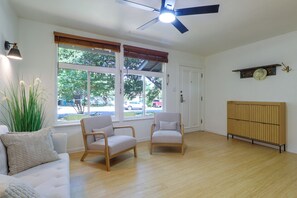 Een kamer met twee fauteuils, een bank, een plafondventilator en een radiator.