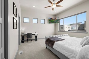 A bedroom with a bed, a desk, and a chair. There is a ceiling fan and a window with a view of buildings. - 3 King Beds | 3 Baths | 2-Car Garage (Poncha Springs)