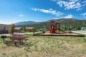 A playground with a slide and climbing structure, picnic tables, and a view of mountains in the background. - 3 King Beds | 3 Baths | 2-Car Garage (Poncha Springs)