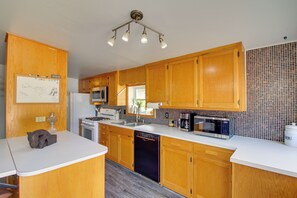 A kitchen with wooden cabinets, a white countertop, a stove, a microwave, and a coffee maker. - 3 Mi to Sandy Shores & More! Fort Walton Beach Apt (Fort Walton Beach)