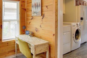 A room with wooden walls, a washing machine, a table with a chair, and a window with blinds. - 3 Mi to Sandy Shores & More! Fort Walton Beach Apt (Fort Walton Beach)