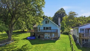 Ein zweistöckiges Haus mit Balkon, umzäunter Garten und Baum.