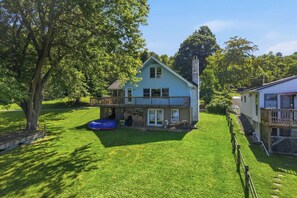 A two-story house with a balcony, a fenced yard, and a tree. - Lakefront Paradise on Lake Wallenpaupack w/ Dock (Hawley)