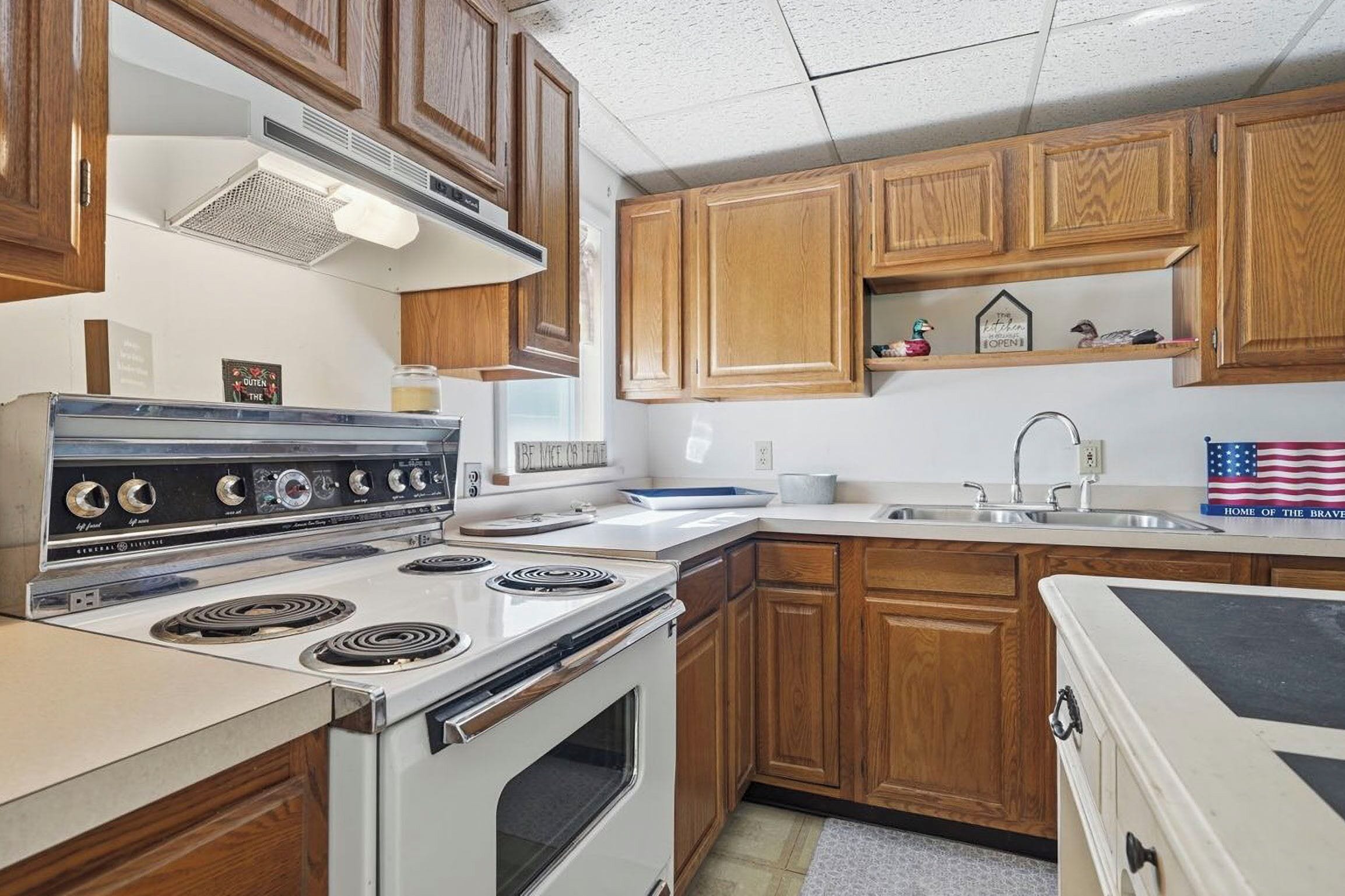 Una cocina con armarios de madera, una estufa blanca y un lavamanos.