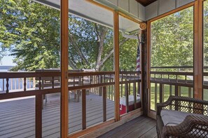 Une terrasse couverte avec des rampes en bois et une chaise en osier.