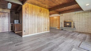 Ein geräumiger Raum mit Holzboden, Kamin und einer Holzwand.