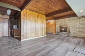 A spacious room with a wooden floor, a fireplace, and a wooden wall partition. - Lakefront Paradise on Lake Wallenpaupack w/ Dock (Hawley)
