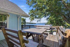 An outdoor deck with wooden benches and tables, overlooking a body of water. - Lakefront Paradise on Lake Wallenpaupack w/ Dock (Hawley)