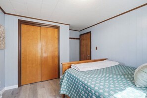 Une chambre à coucher avec une armoire en bois, un lit recouvert d’une couvre-lit à motifs et une tête de lit en bois.