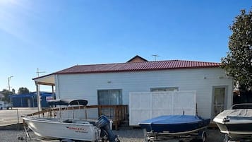 Un pequeño edificio con techo rojo, una zona de amarre cubierta y dos barcos sobre remolques.