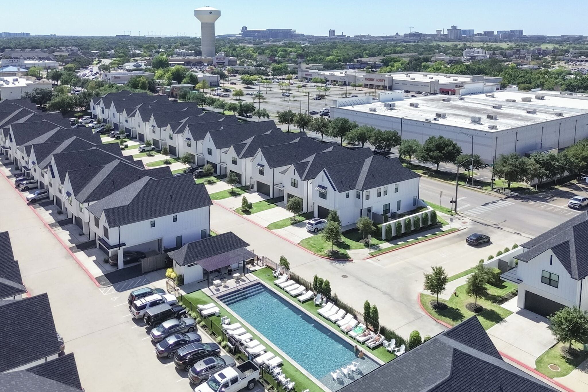 A residential area with modern houses, a swimming pool, and a parking lot.