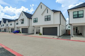 A row of modern two-story houses with attached garages, a red curb, and a blue car parked in front. - Magnolia Manor at College Station & Texas A&M (College Station)